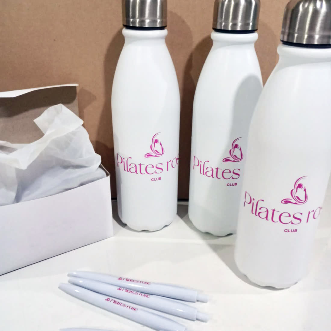 Botellas y bolígrafos con el logo de un estudio de pilates