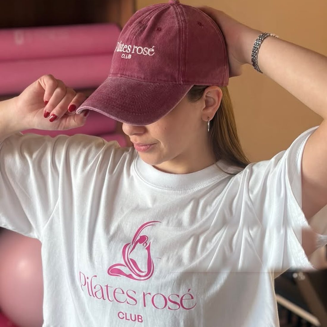 Gorra bordada color cherry y remera blanca estampada de Pilates Rosé Club