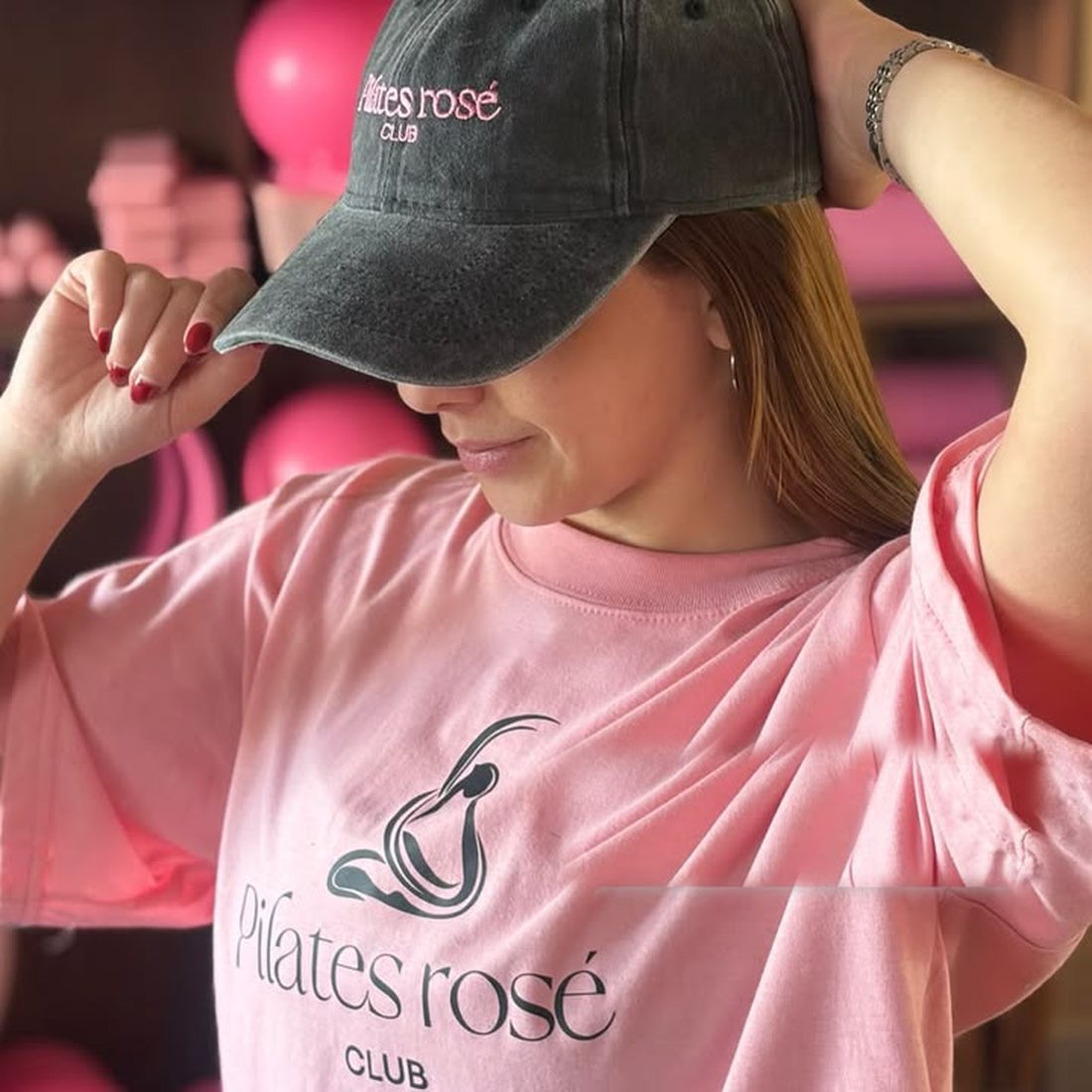 Gorra bordada gris y remera rosa estampada de Pilates Rosé Club